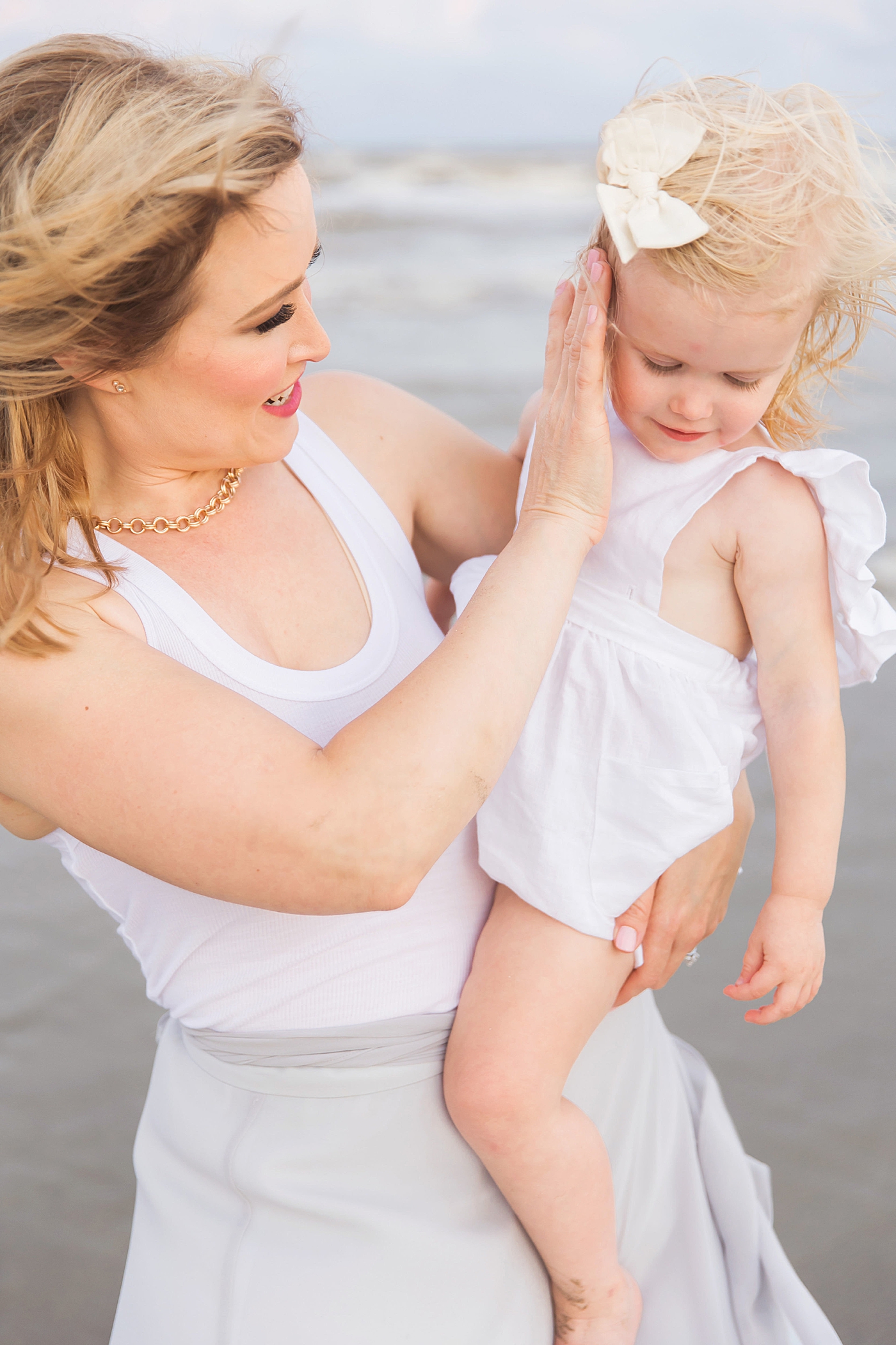 Mom holding her little girl on the beach. Photo by Fresh Light Photography
