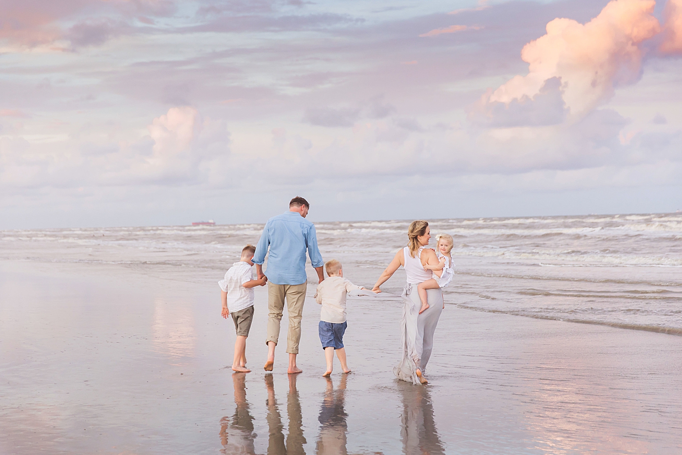 Family of five walking along the water during beach family session. Photo by Fresh Light Photography