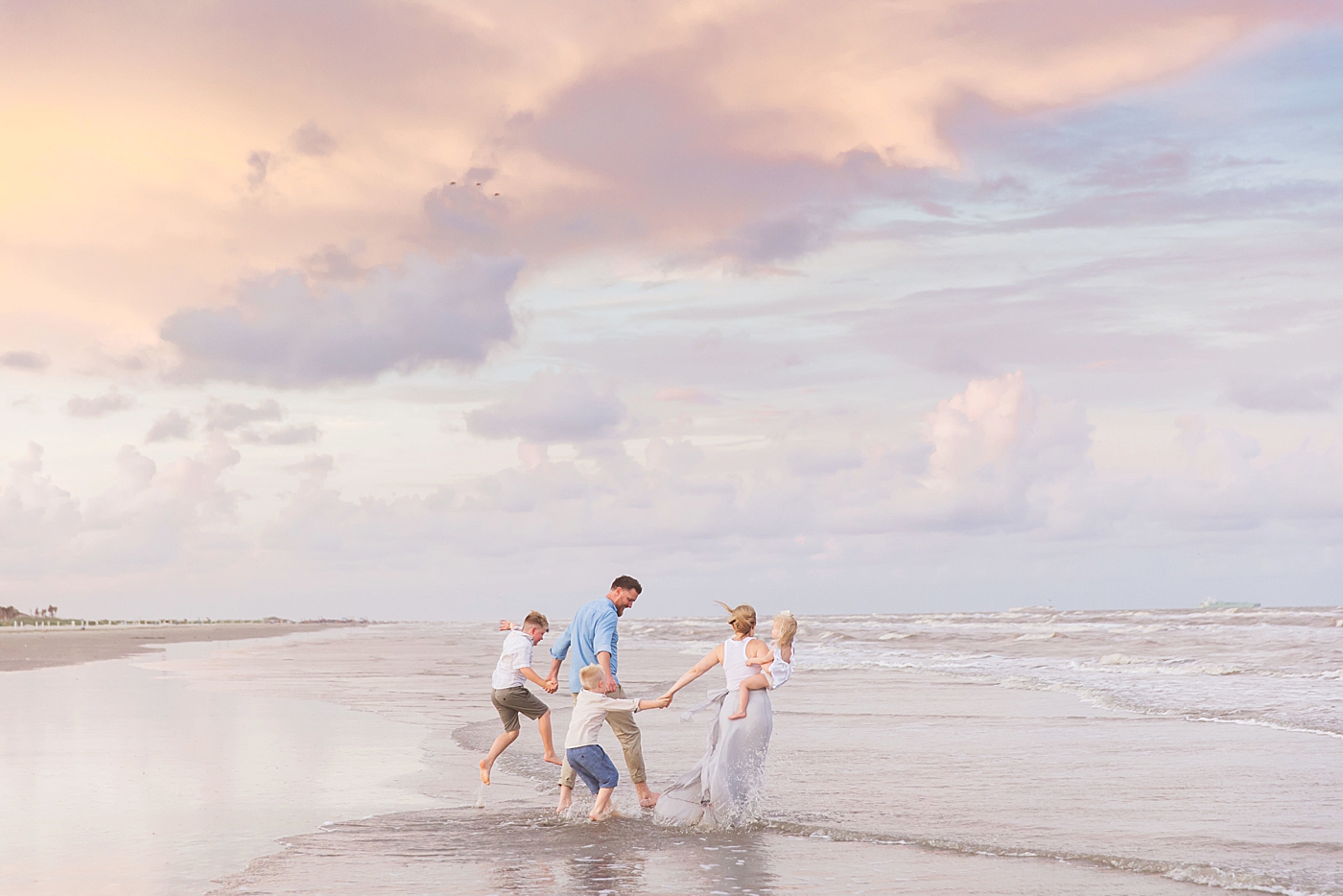 Family playing in the water on the beach during photoshoot. Photo by Fresh Light Photography