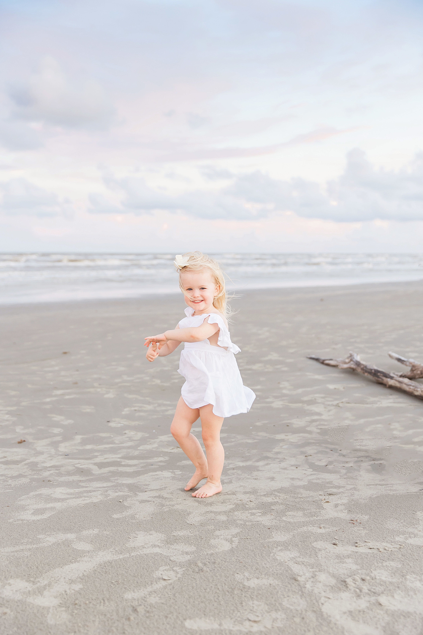 Toddler dancing on the beach during family photoshoot. Photo by Fresh Light Photography