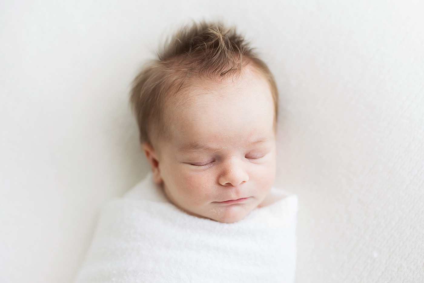 Newborn baby boy with a head full of hair sleeping. Photo by Fresh Light Photography.