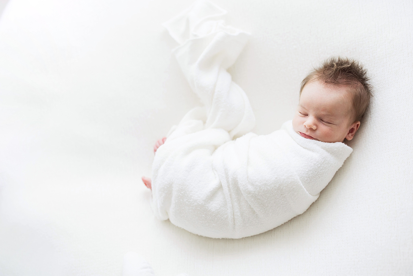Baby boy swaddled in white, sleeping. Photo by Fresh Light Photography.