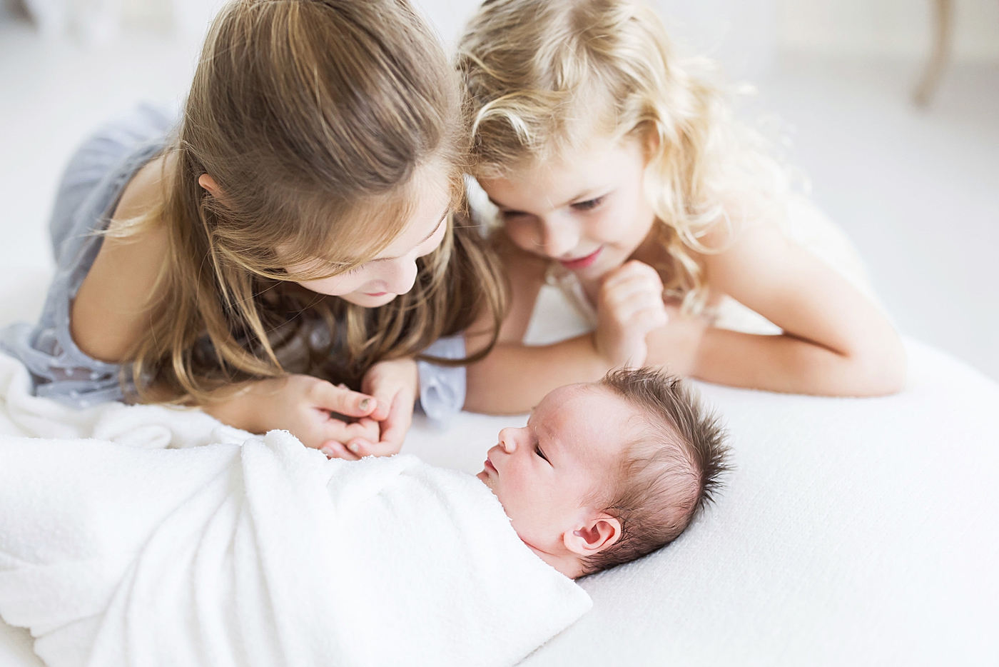 Two big sisters adoring their baby brother. Photo by Fresh Light Photography.