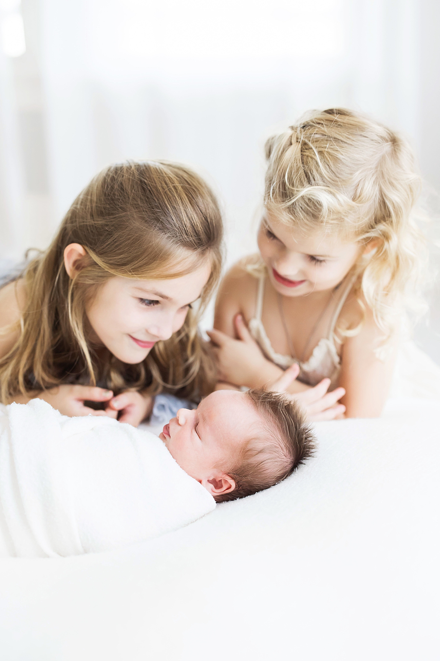 Two big sisters adoring their baby brother. Photo by Fresh Light Photography.