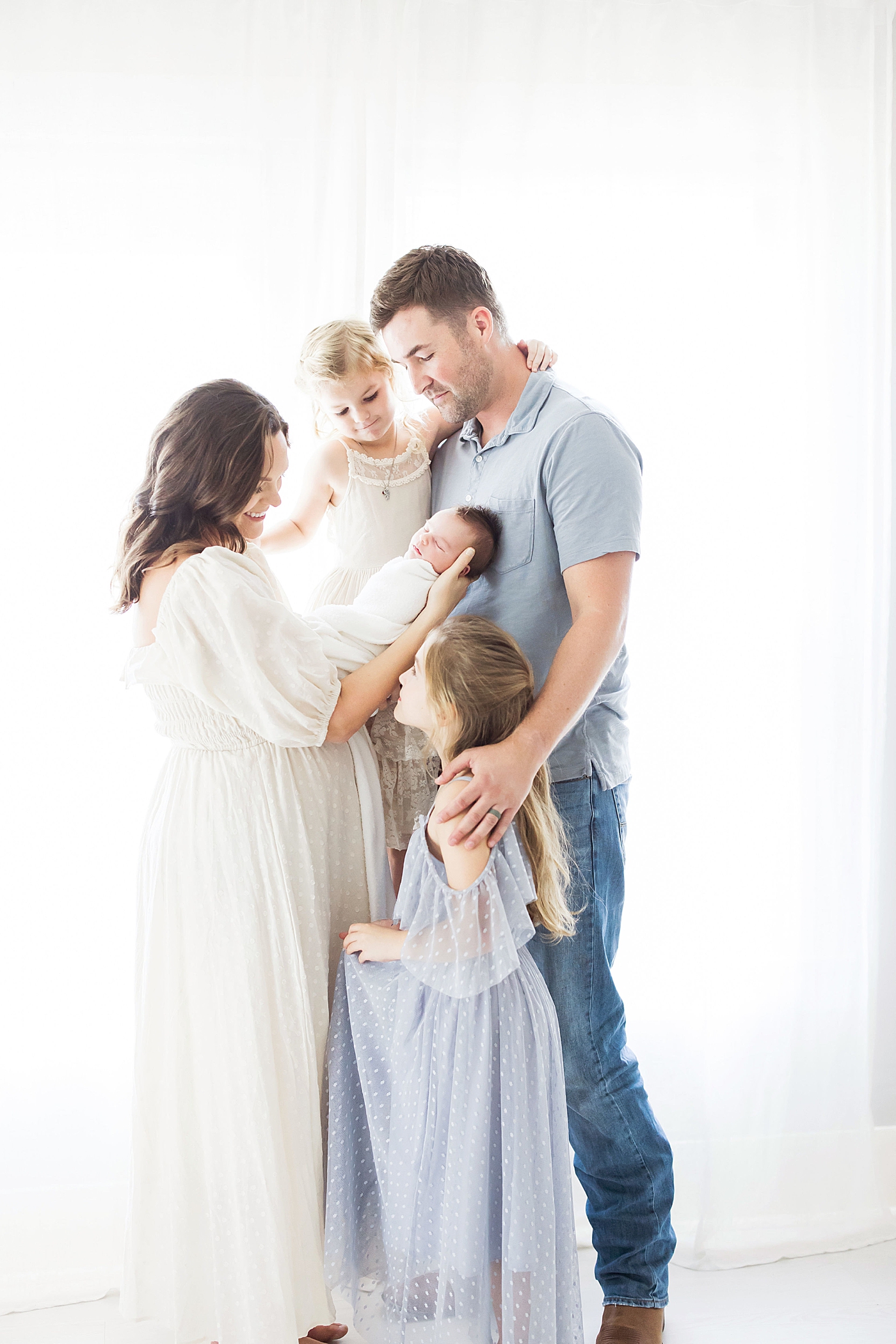 Mom, Dad and two big sisters with their baby brother for newborn photos in Houston with Fresh Light Photography.