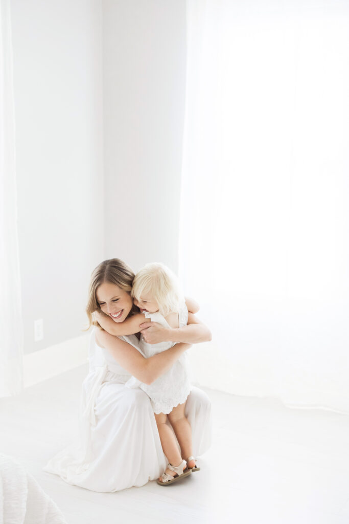 mom hugging daughter in white dress