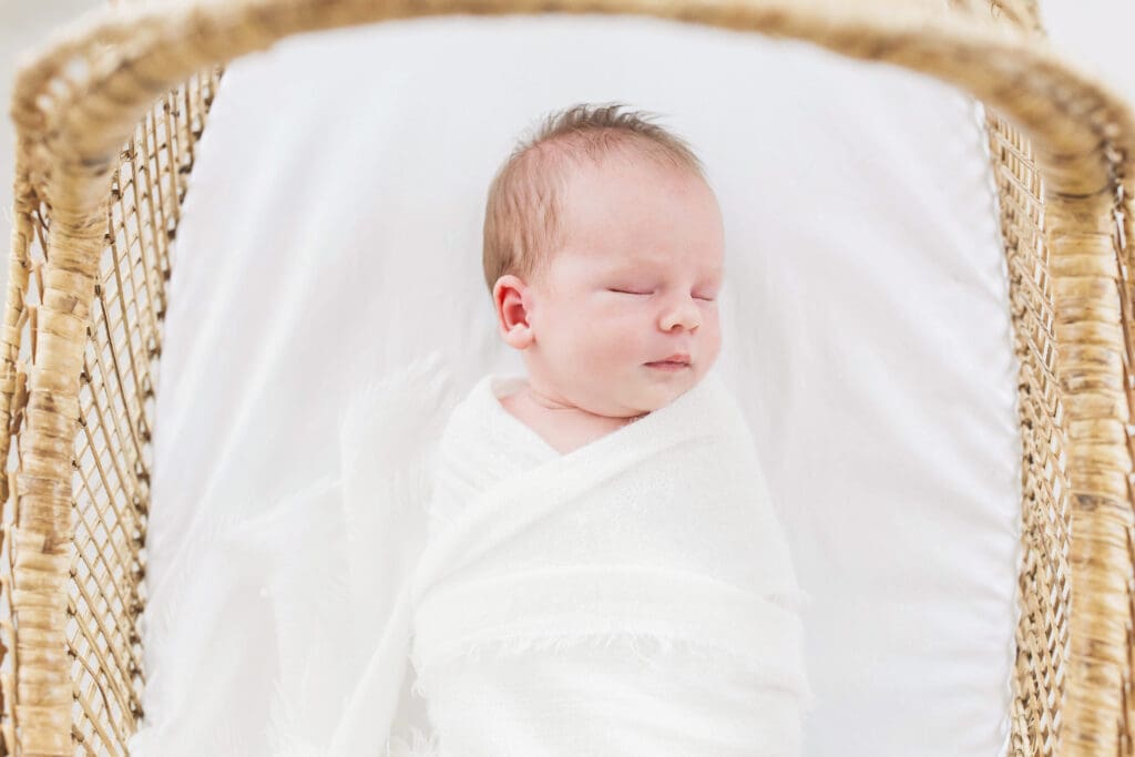 Peacefully sleeping newborn baby wrapped in a soft blanket during a professional newborn photography session in Houston, Texas