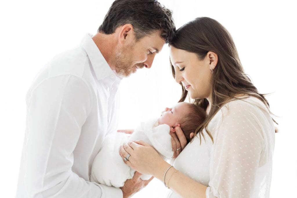 Mother and father holding their newborn baby during a professional newborn photography session in Houston, Texas