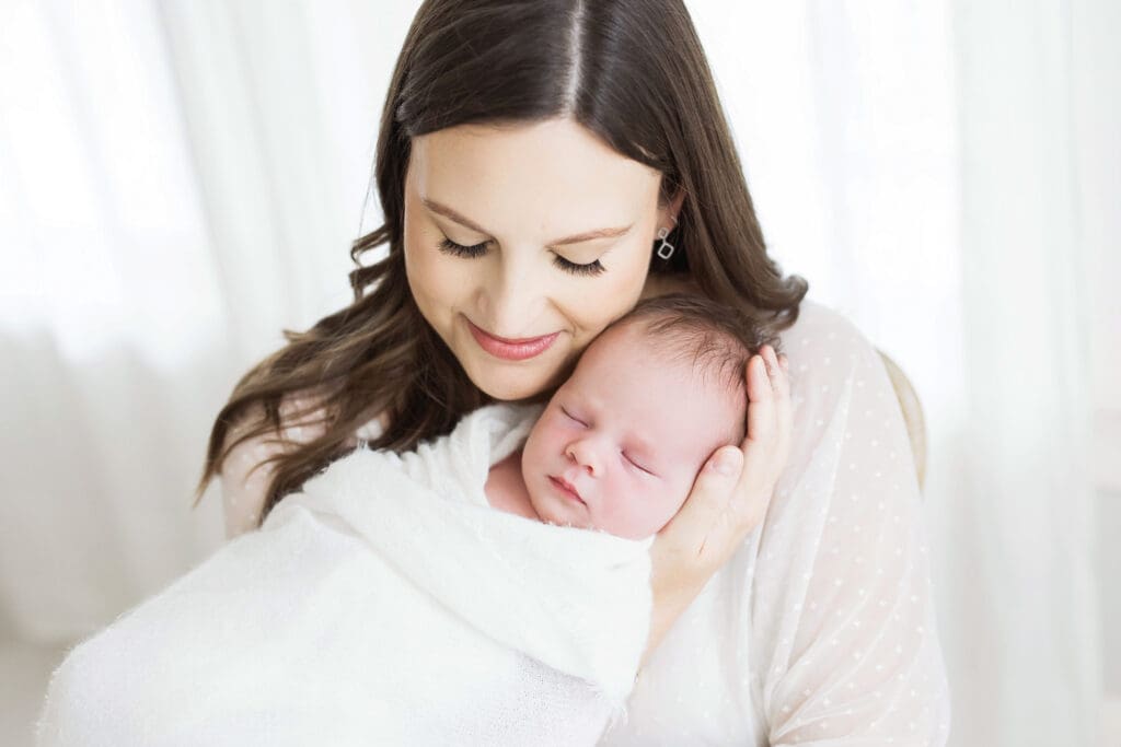 Mother cuddling her newborn baby during a professional newborn photography session in Houston, Texas