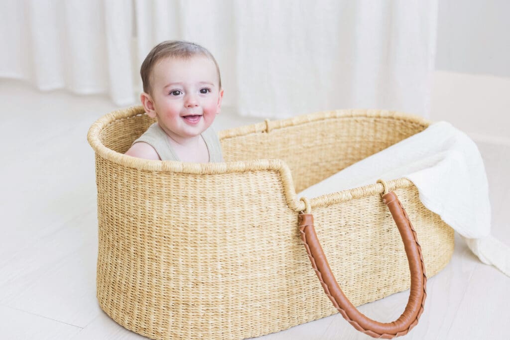 Baby sitting in a woven Moses basket during a studio-based family photography session in Houston Heights, TX