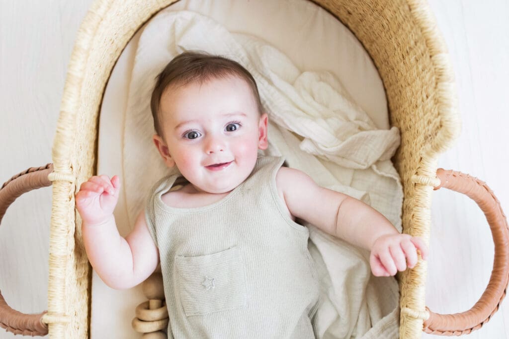 Baby lying in a woven Moses basket during a studio-based family photography session in Houston Heights, TX