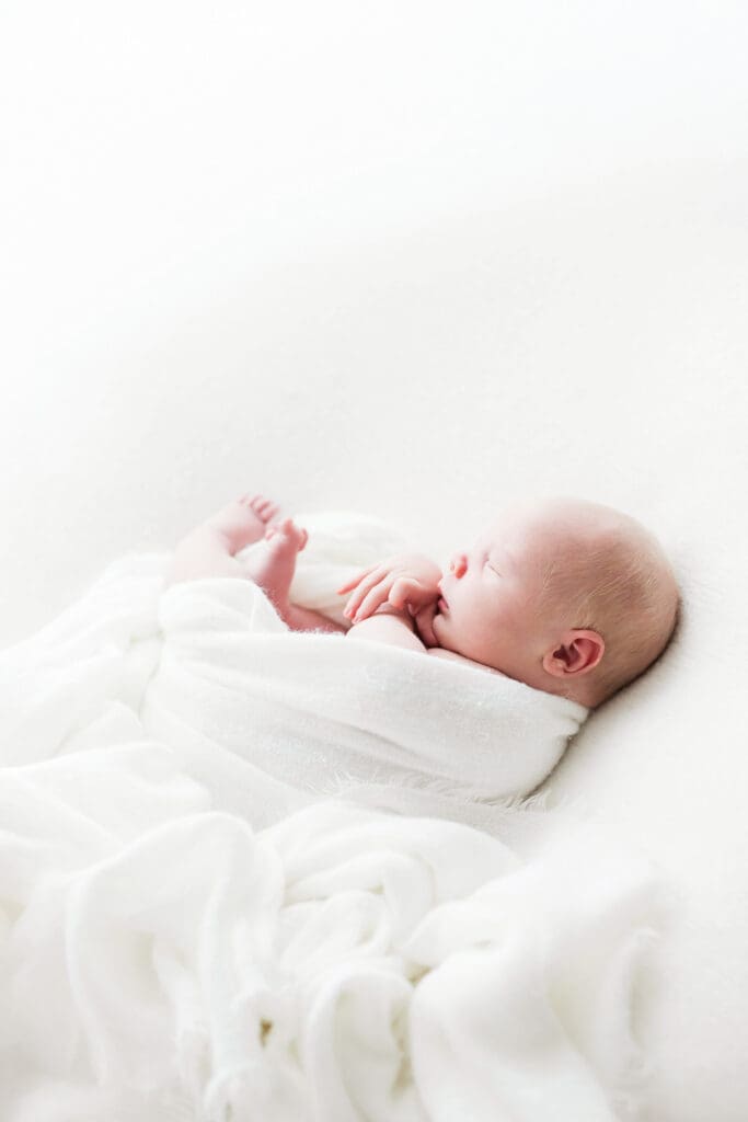Sleeping newborn baby peacefully resting in a cozy wrap during a professional newborn photography session in Houston Heights, TX.