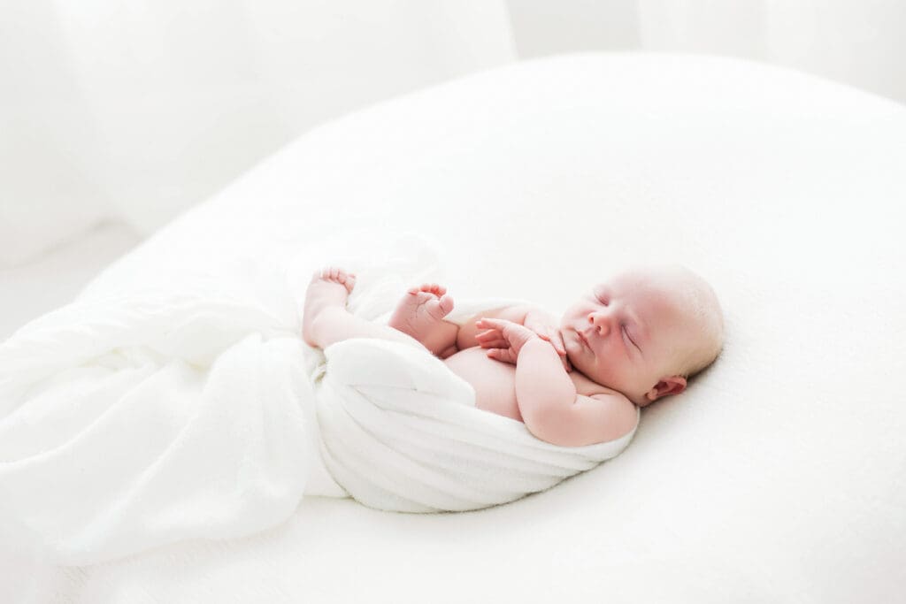 Peacefully sleeping newborn baby wrapped in a soft blanket during a newborn photography session in Houston Heights, TX.