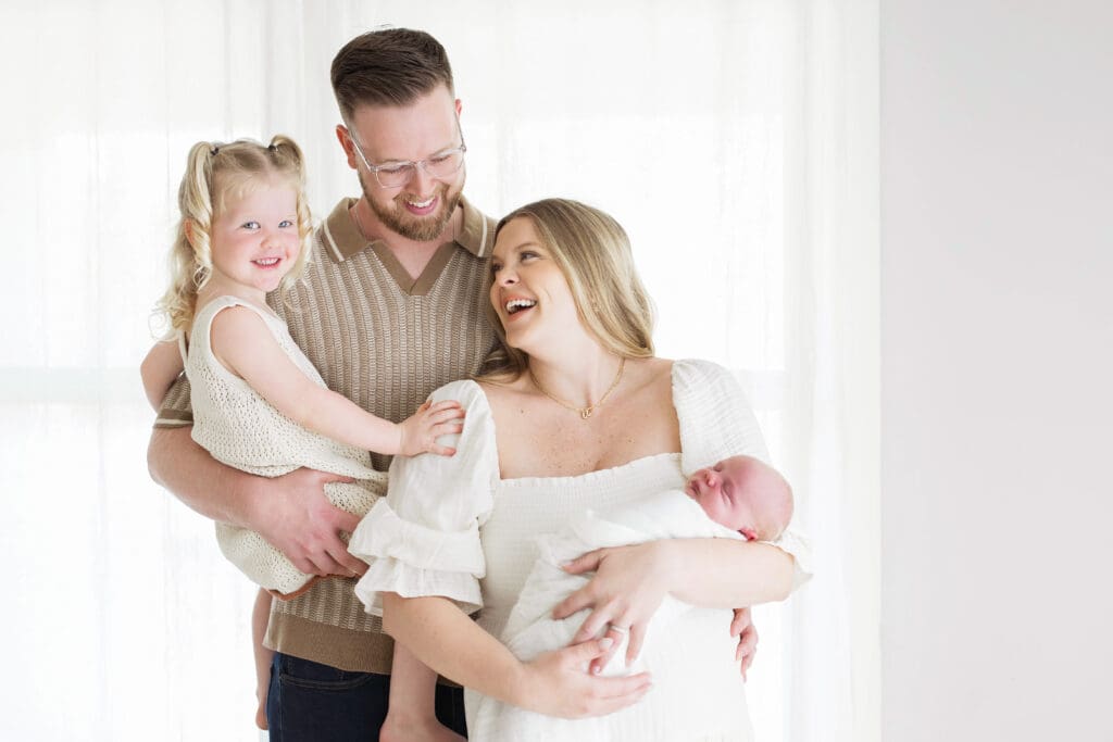 Mom and dad cuddling their newborn baby during a family photography session in Houston Heights, TX, capturing a loving and intimate family moment.