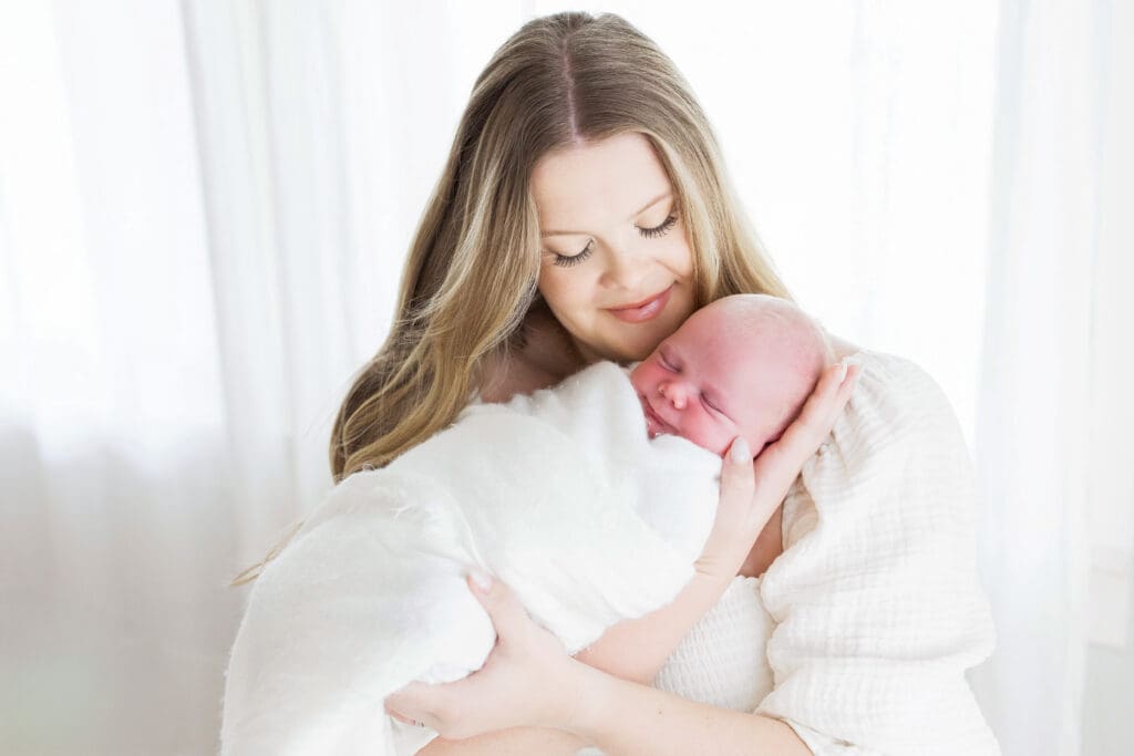 Mother lovingly holding her newborn baby during a cozy lifestyle photography session in Houston Heights, TX, capturing a tender and emotional bonding moment.