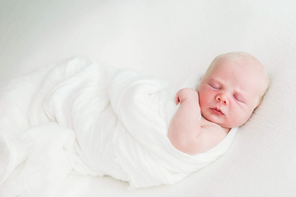Newborn baby sleeping peacefully with a gentle smile during a professional newborn photography session in Houston Heights, TX.