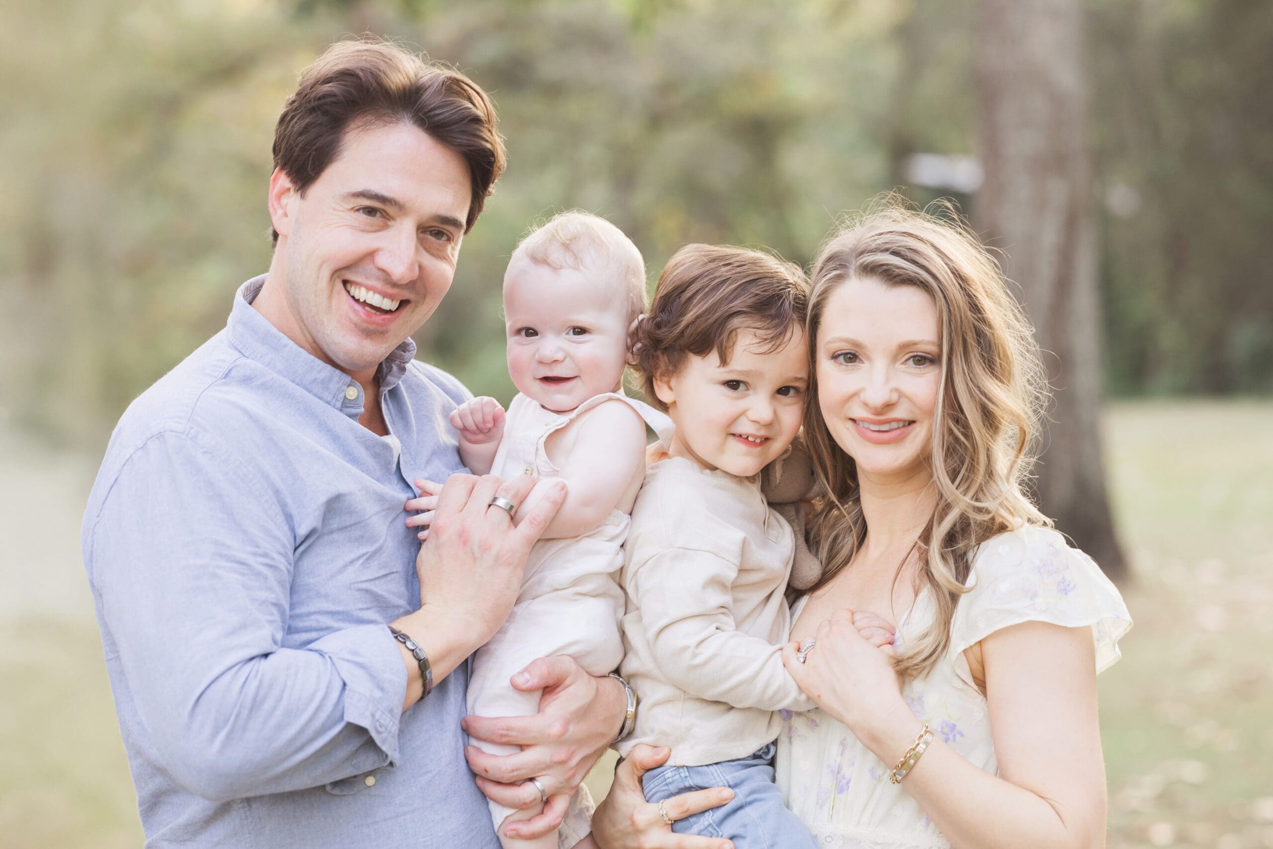Smiling family of three with their baby during a fall outdoor family photography session in Houston.